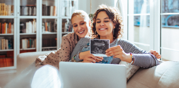 Deux femmes regardent une échographie sur un canapé