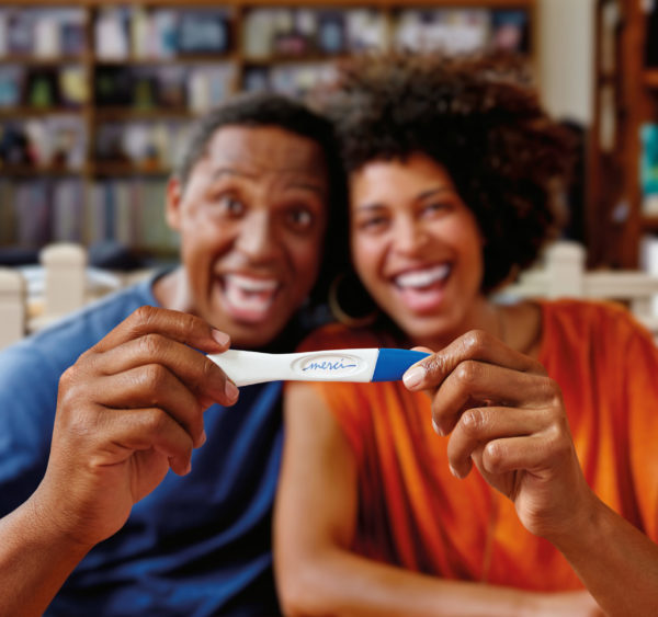 Un couple tient un test de grossesse avec le mot 