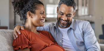 un couple souriant en s'enlaçant sur le canapé