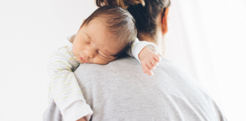 une femme fait un câlin à un bébé endormi