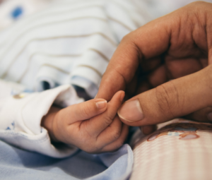 Une maman tient le doigt de son nouveau né